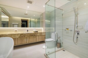 Een moderne badkamer met een douchecabine van glas, een vrijstaand bad en een wastafel met een marmeren aanrechtblad.