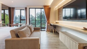 Una camera d'albergo moderna con un letto grande, una poltrona e una scrivania, e un televisore.