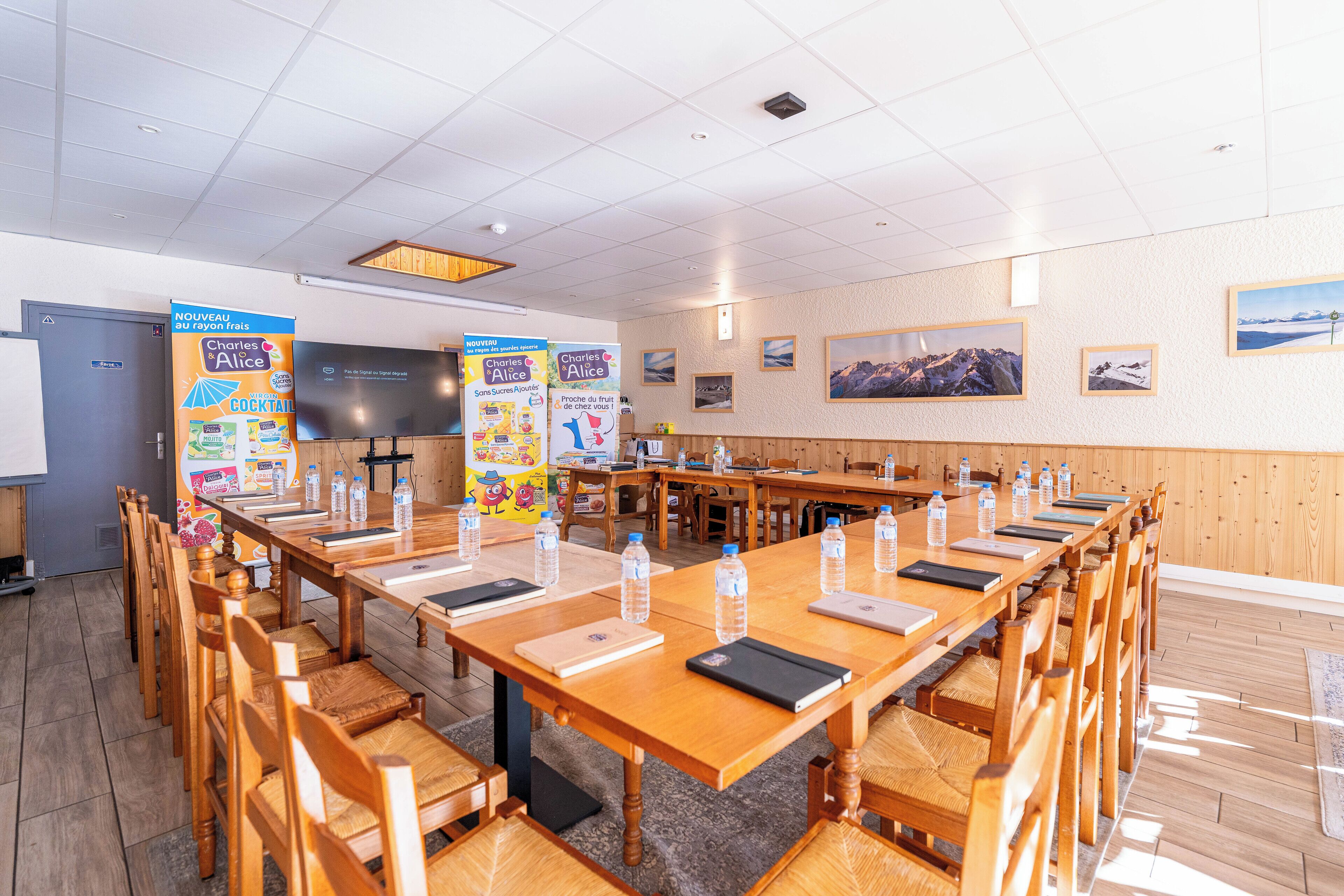 A conference room with wooden tables and chairs, a whiteboard, and posters on the walls.