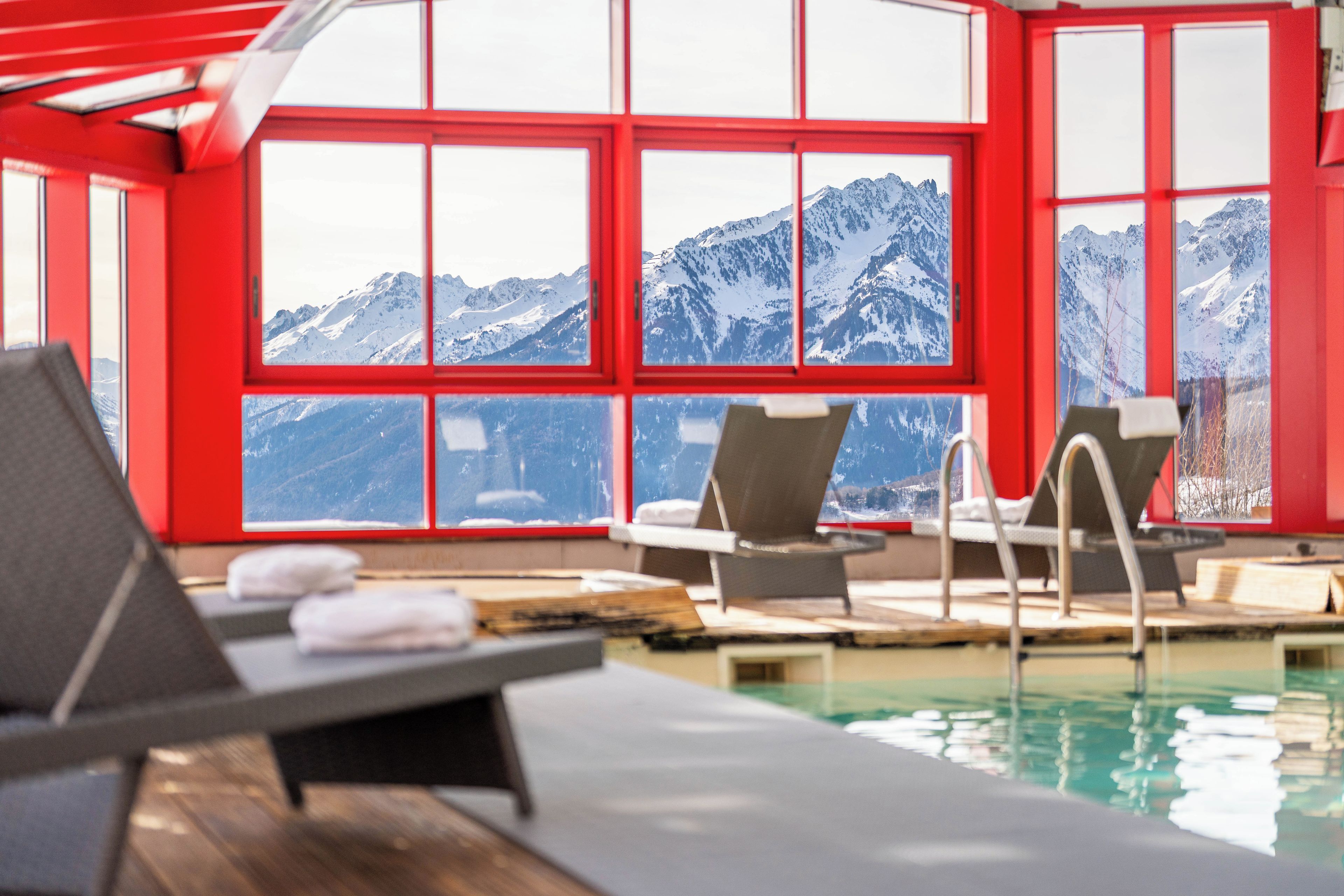 An indoor swimming pool with a view of snow-capped mountains through large windows.