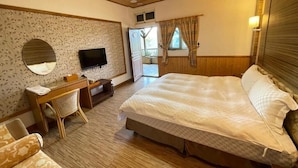 Un dormitorio con cama, escritorio, silla, televisor y ventana con cortinas.