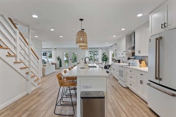 A modern kitchen with white cabinetry, a central island, and a staircase with wooden railings.