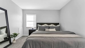 Une chambre à coucher avec un lit, une table de chevet, un miroir et une fenêtre.