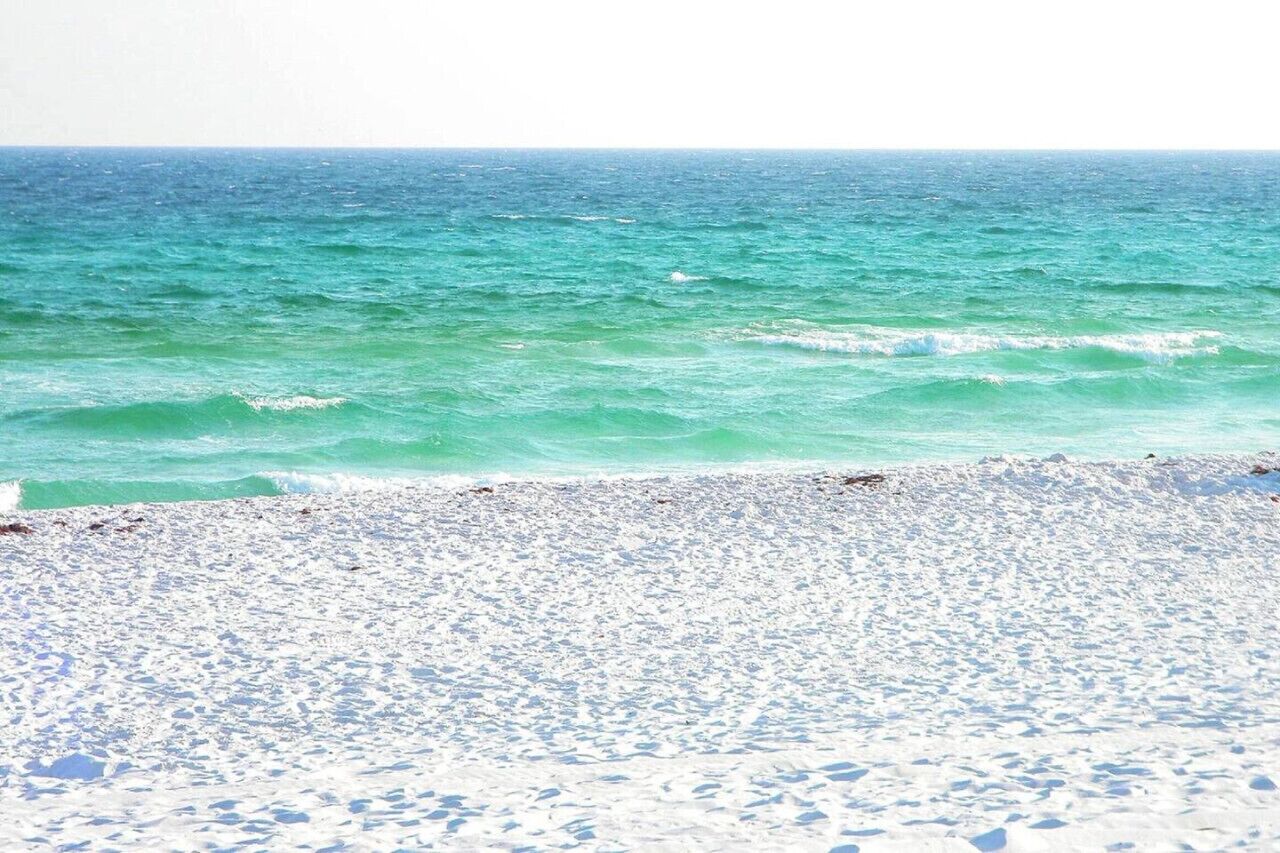 Ein Strand mit klarem türkisblauem Wasser und weißem Sand.