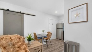 Eine moderne Küche mit einem Edelstahl-Kühlschrank, einem Essbereich mit rundem Tisch und Korbstühlen sowie einem Schiebetürenschrank.