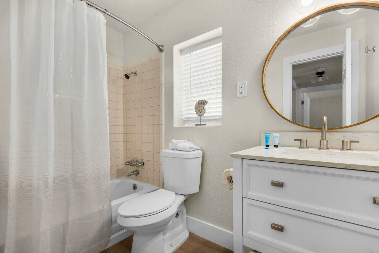 A bathroom with a toilet, shower, and sink.