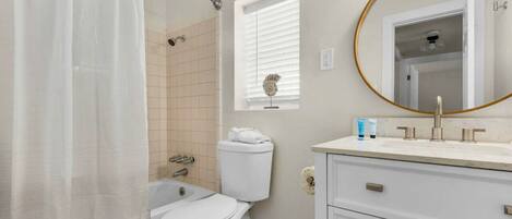 A bathroom with a toilet, shower, and sink.