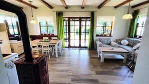Una sala de estar acogedora con suelo de madera, un comedor con mesa y sillas, y un sofá con un cojín estampado.
