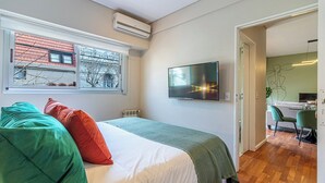 Un dormitorio con una cama, un televisor y una ventana.