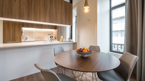 Een moderne keuken met houten keukenkastjes, een ronde eettafel met stoelen en een schaal met fruit.