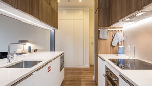 Een moderne keuken met houten kastjes, een wit aanrecht en roestvrijstalen apparatuur.