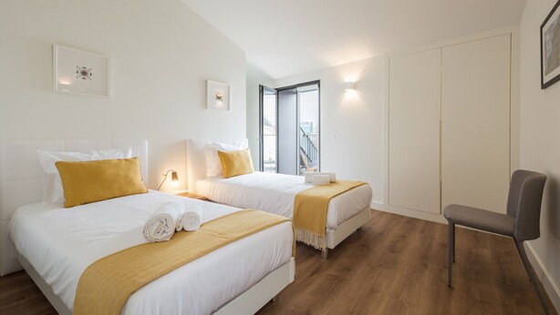 Ein Hotelzimmer mit zwei Betten, einem Sessel, einem Schreibtisch und einem Fenster mit Blick.