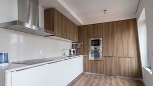 Eine moderne Küche mit weißen Schränken, einer Edelstahl-Dunstabzugshaube, einer Mikrowelle und einem Backofen.