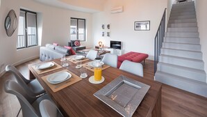 Ein modernes Wohnzimmer mit Essbereich, einer Treppe und einem Balkon.