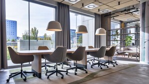 Una sala de conferencias moderna con una larga mesa, seis sillas de oficina e iluminación colgante.
