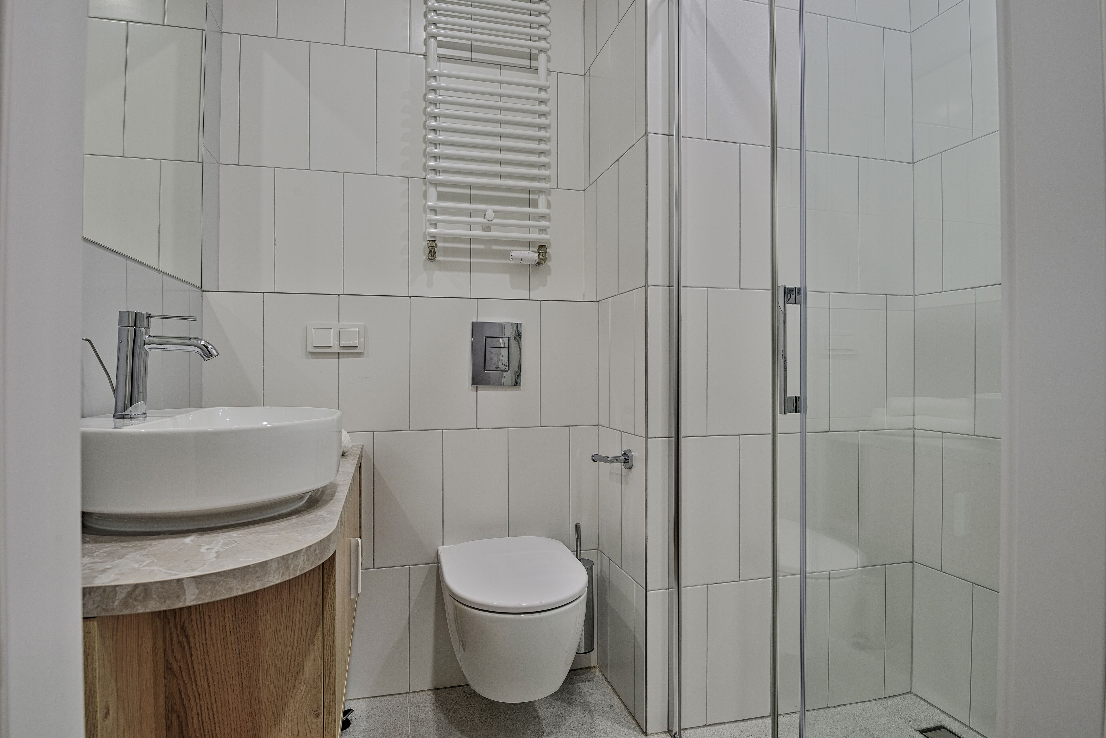 A modern bathroom with a sink, toilet, and glass shower enclosure.