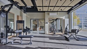 Un gimnasio moderno con diversos equipos de ejercicio, ventanas amplias y un diseño limpio y abierto.