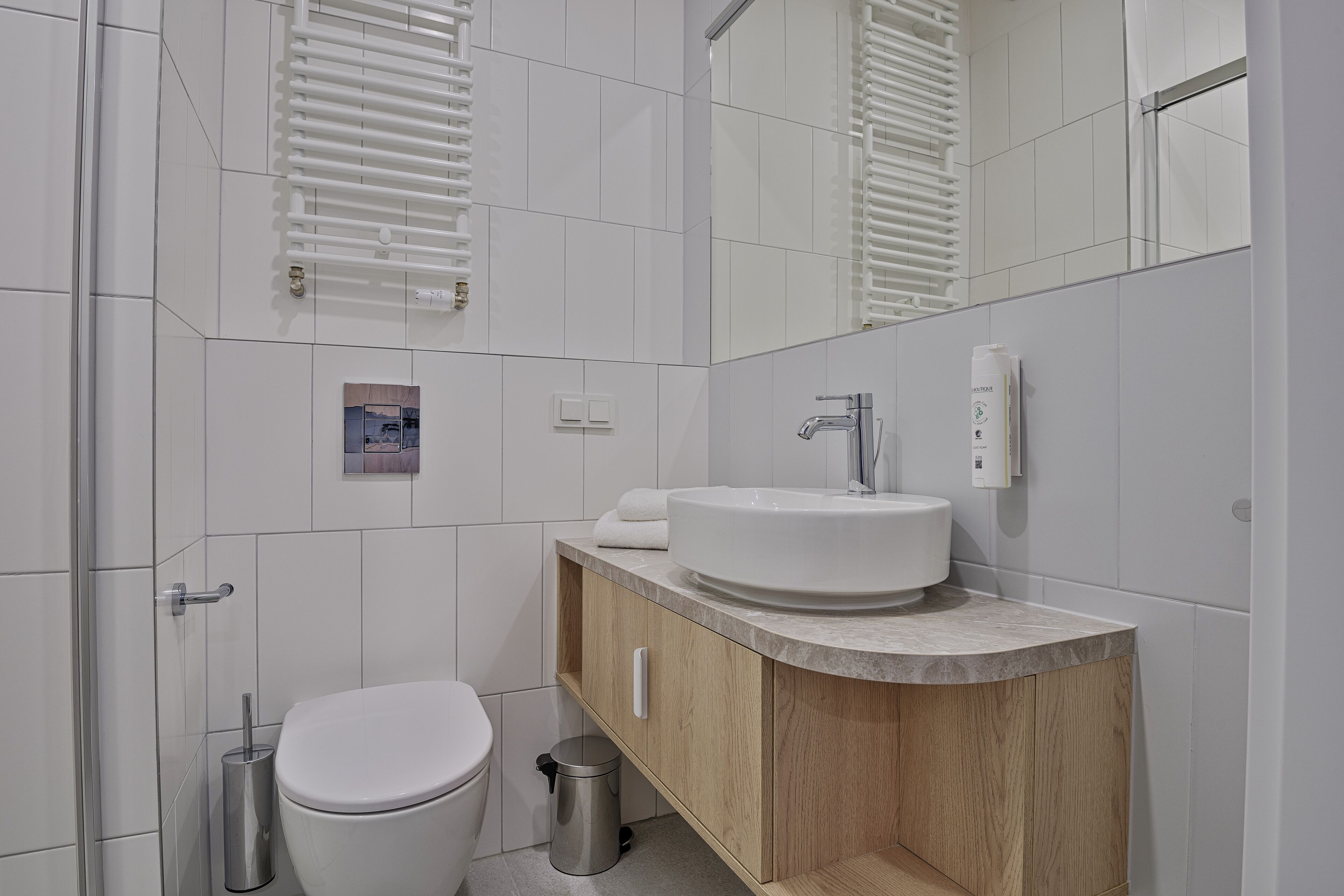 A modern bathroom with a white toilet, a wooden vanity with a sink, and a mirror.