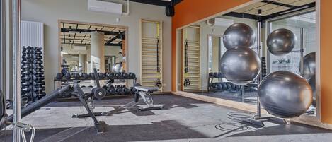 A gym with exercise equipment, mirrors, and a wall-mounted air conditioning unit.
