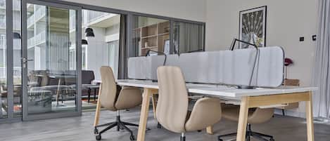 A modern office space with glass walls, a white table, and ergonomic chairs.