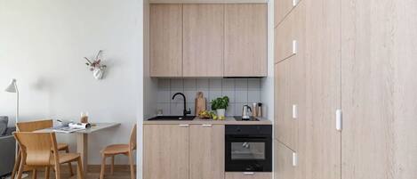 Una cocina moderna con armarios de madera, un horno negro y un comedor con mesa y sillas.