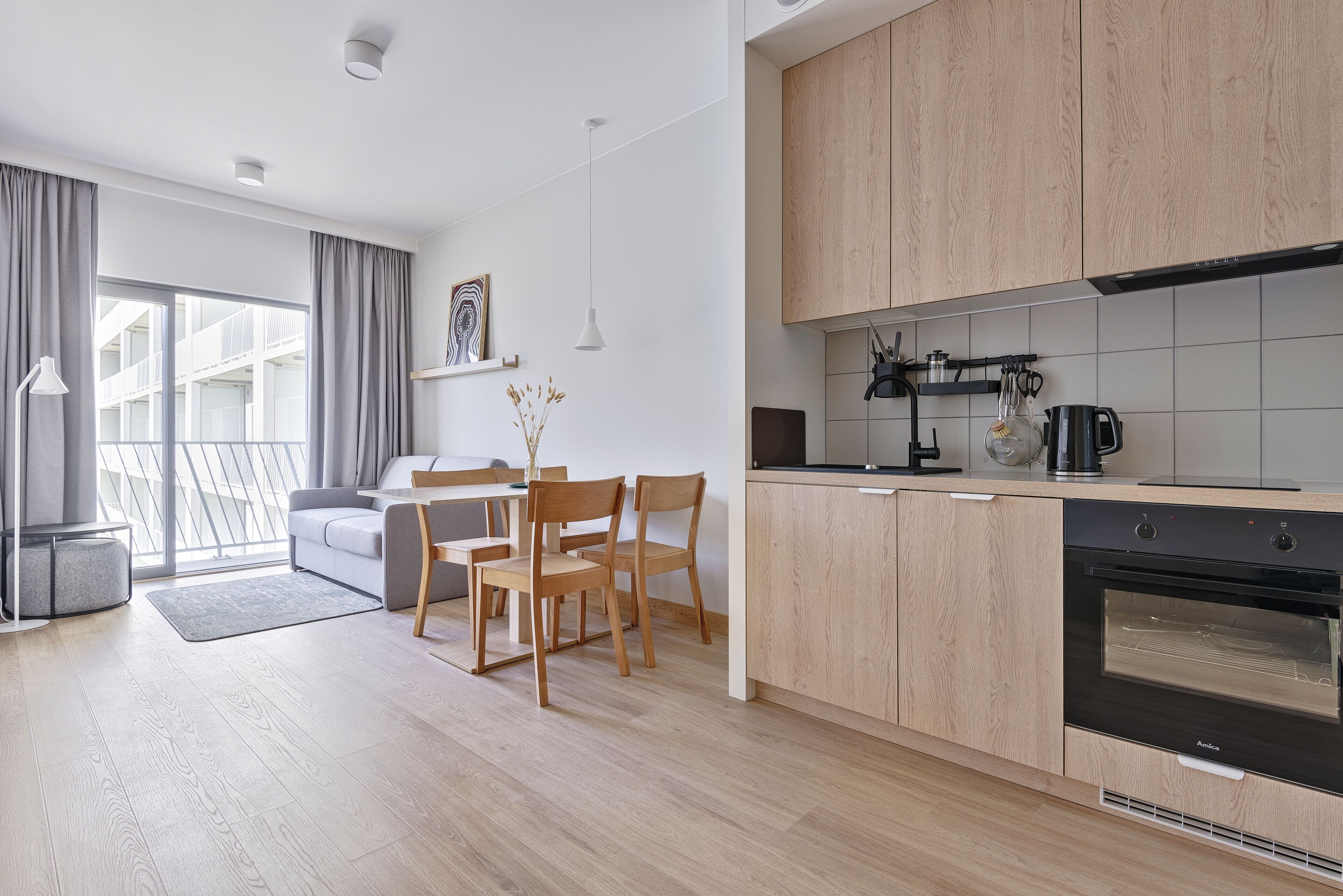 Una cocina moderna con armarios de madera, horno empotrado y comedor con mesa y sillas.