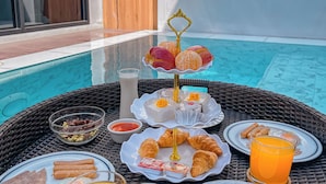 A dining table with plates of food, drinks, and a fruit display. - KVILLA (Bangkok)