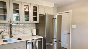 A modern kitchen with stainless steel appliances, white cabinetry, and a tiled backsplash. - Enjoy your stay in this cozy, newly renovated condo in the heart of German Village (Columbus)