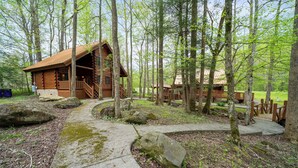 A log cabin with a porch and a stone pathway. - Parkway Treasure - 3BR/New Hot Tub/New Firepit/Grill/Sleeps 12 (Gatlinburg)