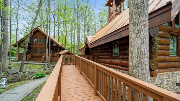 A wooden log cabin with a wooden deck and stone walls. - Parkway Treasure - 3BR/New Hot Tub/New Firepit/Grill/Sleeps 12 (Gatlinburg)
