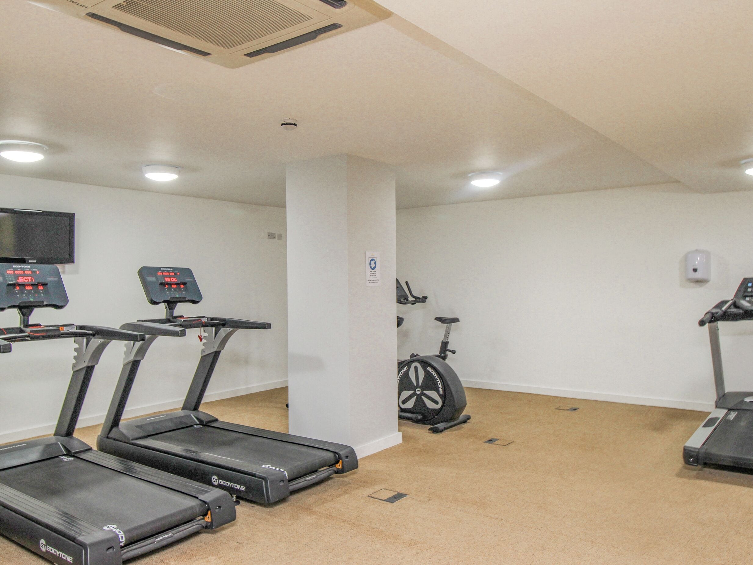 A gym with treadmills, a stationary bike, and a wall-mounted TV.