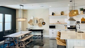 A modern kitchen with white cabinets, a central island, and a hanging pendant light.
