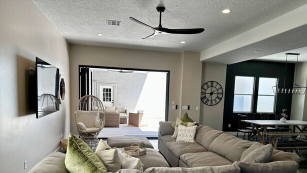 A modern living room with a sectional sofa, a dining area, and a large window.