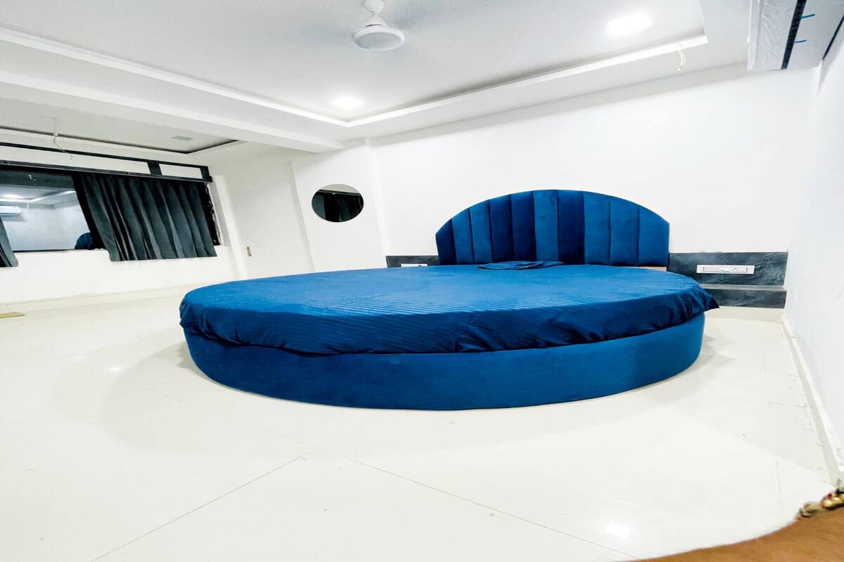 A modern bedroom with a circular bed, a round mirror, and a ceiling fan.