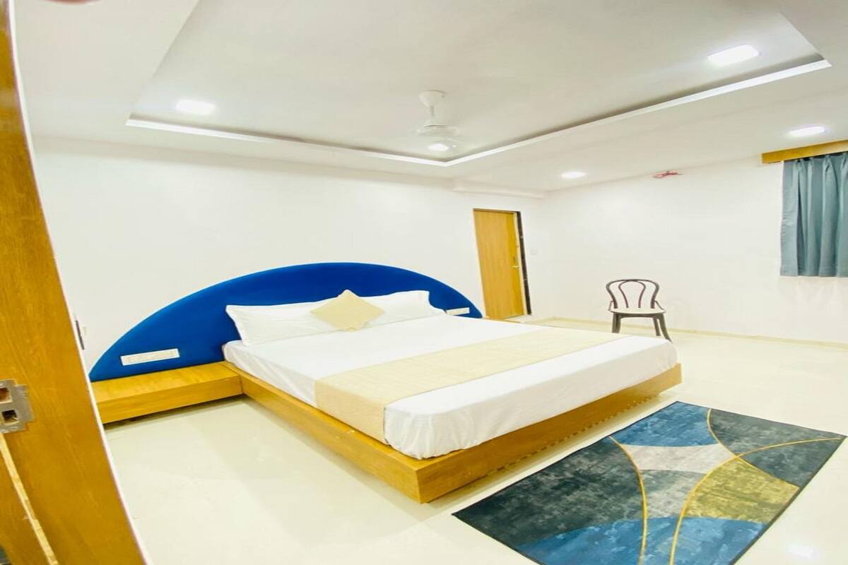 A bedroom with a bed, a chair, and a window.