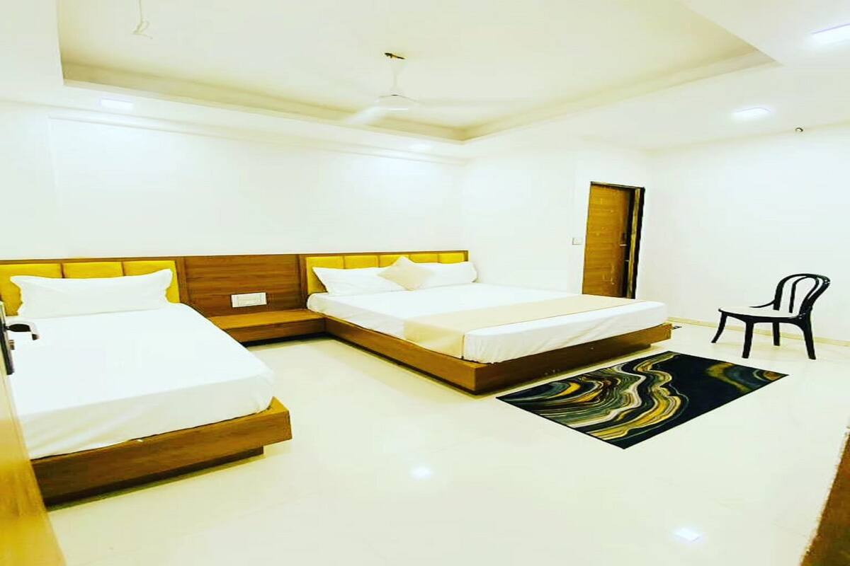 A modern bedroom with two beds, a chair, and a ceiling fan.