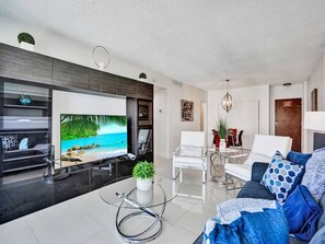 A modern living room with a flat-screen TV, a glass coffee table, and a sofa with patterned cushions. - New! New! beach view (Hollywood)
