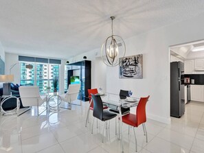 A modern living room with a dining area, a kitchen, and large windows offering a city view. - New! New! beach view (Hollywood)
