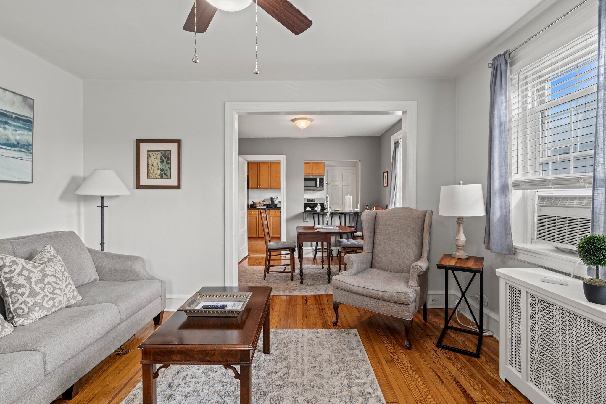 A living room with a sofa, armchair, coffee table, and a dining area with a table and chairs.