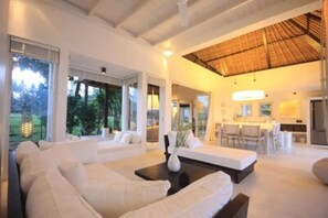 Relax in a spacious living area with a high ceiling, two sofas, and a dining table.