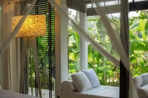 Relax in comfort with a sofa facing a lush green view through a large window, framed by a black grill.