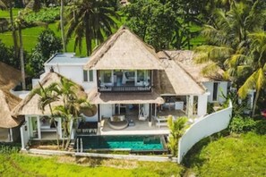 A two-story house with a thatched roof, a swimming pool, and lush greenery. - “Summer Moon, Ricefield Sunset front Private Pool” (Gianyar,)
