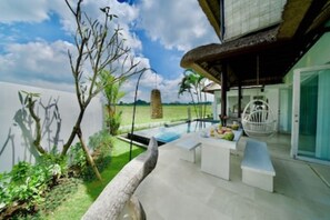 A modern outdoor area with a pool, seating, and a hanging chair. - “Summer Moon, Ricefield Sunset front Private Pool” (Gianyar,)