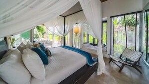 Een slaapkamer met een bed, witte gordijnen, een raam en een stoel.