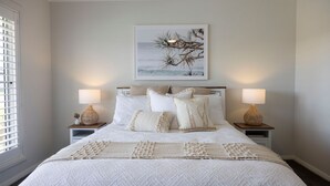 A bedroom with a bed, two bedside tables, a nightstand, a window with blinds, and a wall-mounted picture. - Spoondrift - 5 Mins Walk to Beach (South West Rocks)