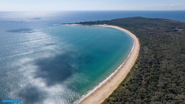 An aerial view of a coastal area with a sandy beach and dense forest. - Spoondrift - 5 Mins Walk to Beach (South West Rocks)