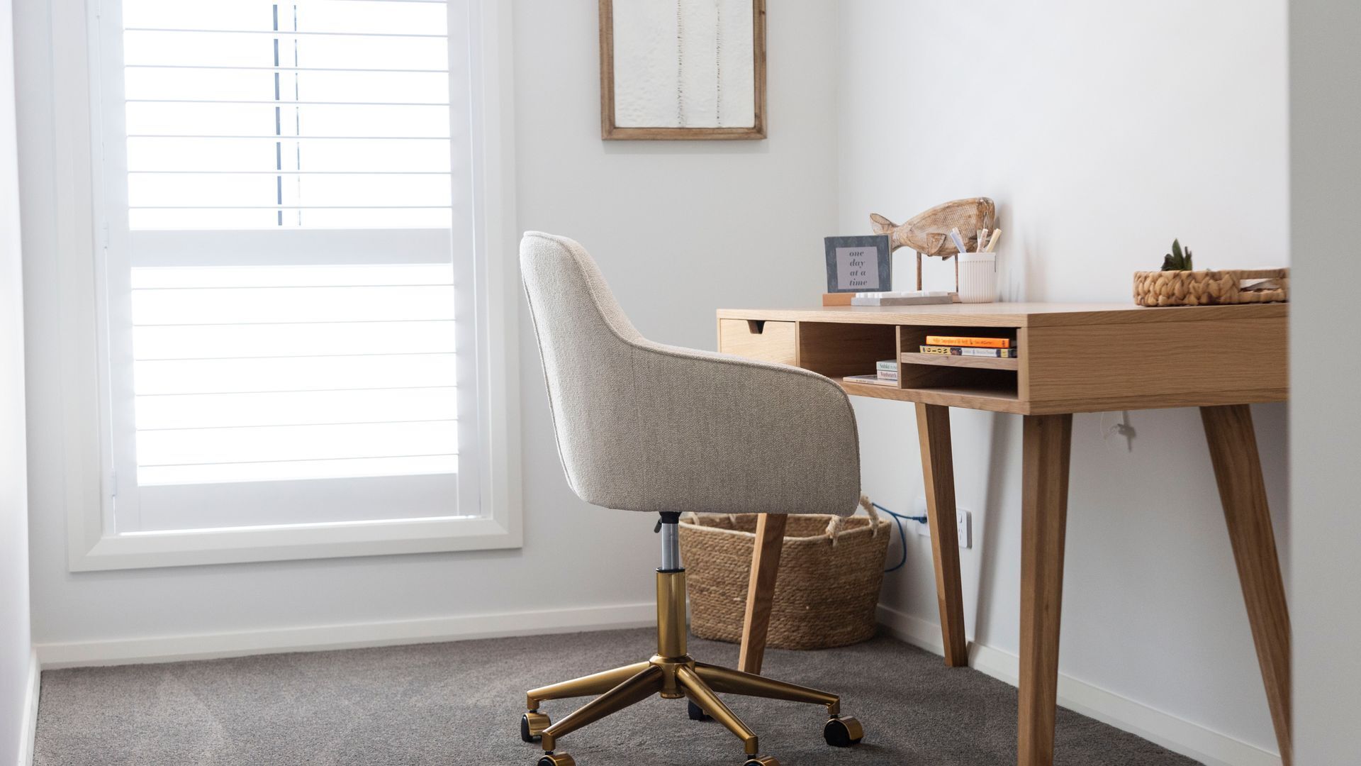 Un fauteuil de bureau moderne doté d’un haut dossier et d’un piétement à cinq branches, placé devant un bureau en bois muni d’une étagère.