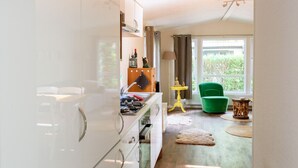 A modern kitchen with white cabinets, a green chair, and a yellow table.