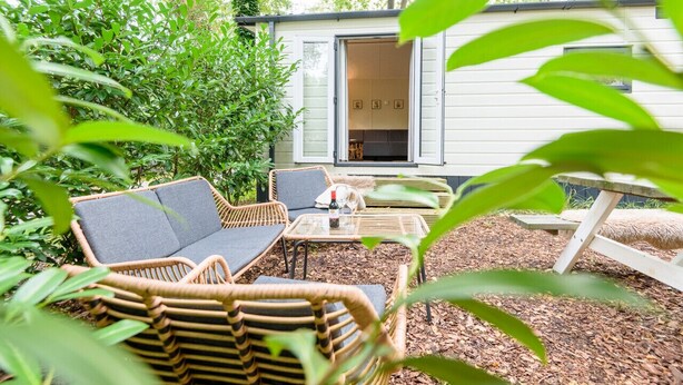 A cozy outdoor seating area with wicker furniture, a small table, and a wooden bench.
