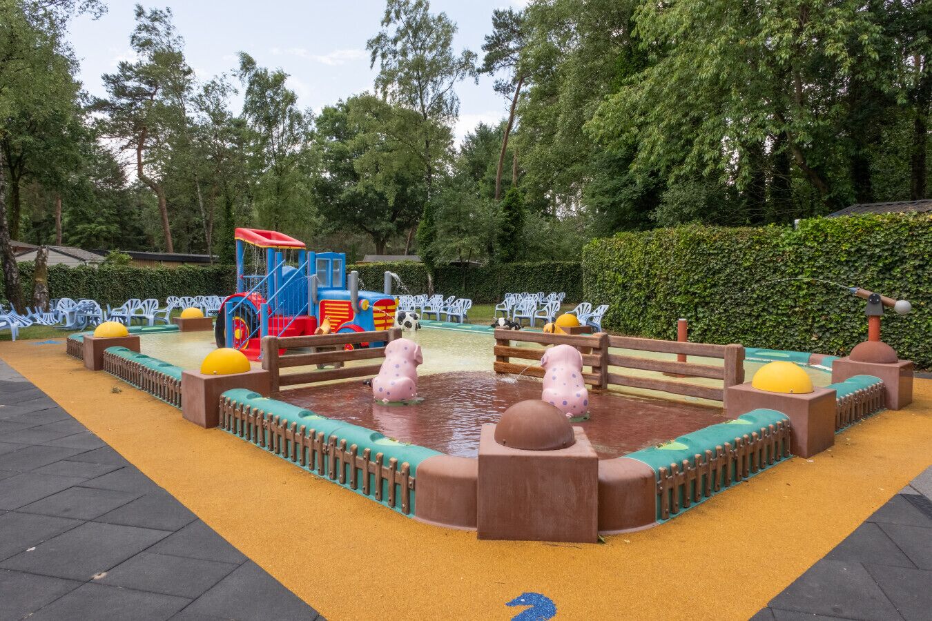 A playground with a water play area, benches, and a train ride.